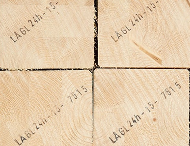 Gestapelte Brettschichtholzbalken mit sichtbarer Jahresringstruktur und Markierungen für den Holzbau.