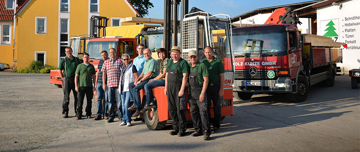 Mitarbeiter von Holz Kunze vor Fuhrpark und Firmengebäude