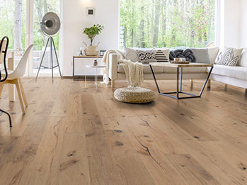 Im Wohnzimmer wurde Parkett in Langdielen-Optik verlegt. Ein Sofa und einige liebevoll platzierte Dekoelemente runden das gemütliche Ambiente ab.