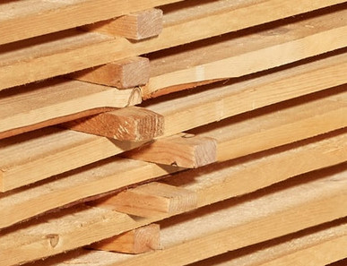 Gestapelte Schalbretter aus Holz mit sägerauer Oberfläche, ideal für den Bau- und Konstruktionsbereich.